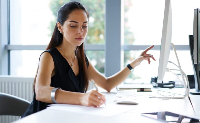 Skilled worker points to screen while taking notes