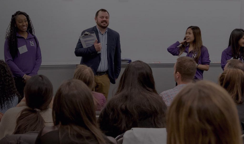 A background image for Northwestern Medill of a professor giving a speech