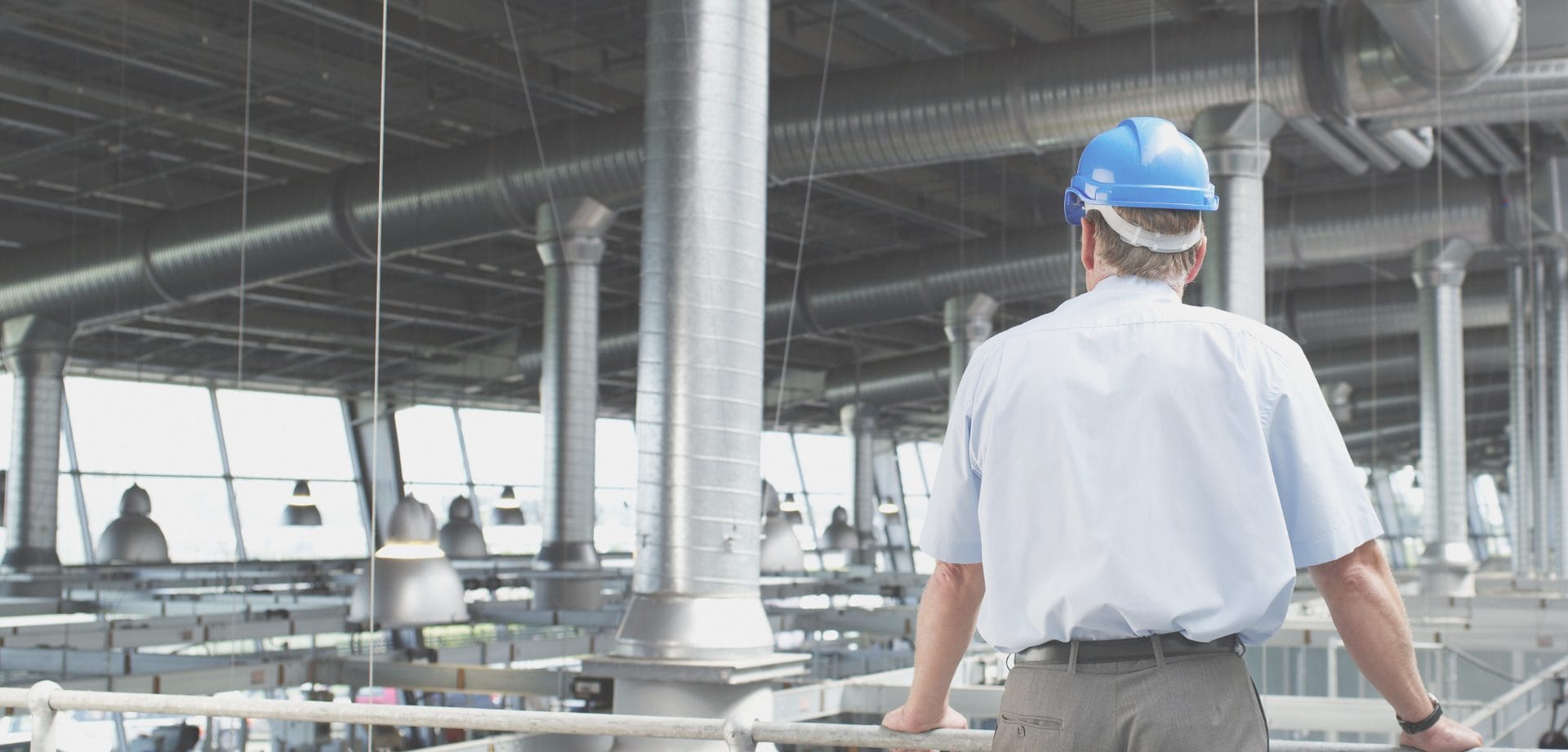 A man in a hardhat looks at a collection of vents